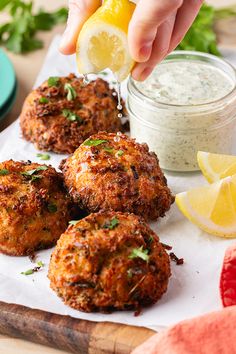 a person is squeezing lemon into some crab cakes