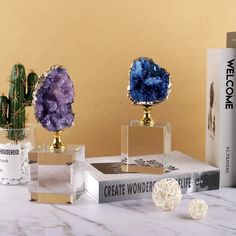 three crystal sculptures sitting on top of a table next to books and cacti