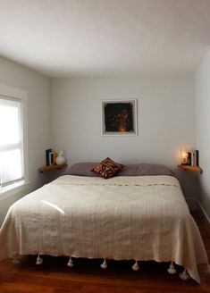 a bed sitting in a bedroom next to a window on top of a hard wood floor