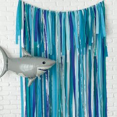 a shark hanging from the side of a wall next to blue streamers and a white brick wall