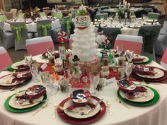 the table is set for christmas dinner with red and green plates, silverware, and candy canes