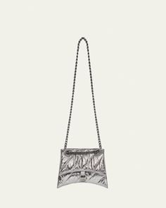 Balenciaga "Crush" shoulder bag in pad quilted metallic calf leather     Tonal sliding chain shoulder strap can be doubled     Flap top with magnetic closure; hanging B logo medallion     Center slip compartment divides interior; one zip pocket     Approx. 6.3"H x 10.2"W x 2.7"D    Made in Italy Luxury Silver Shoulder Bag With Metal Logo, Silver Bag With Metal Logo For Everyday Use, Luxury Silver Shoulder Bag With Chain Strap, Silver Evening Bag With Metal Logo, Luxury Silver Shoulder Bag With Chain, Silver Leather Wallet On Chain With Chain Strap, Silver Leather Wallet On Chain For Evening, Silver Leather Wallet On Chain, Silver Wallet On Chain For Everyday Use