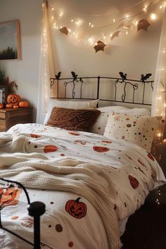 a bed with pumpkins and lights on the headboard is decorated in white linens