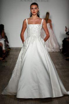 a woman in a white wedding dress on the runway