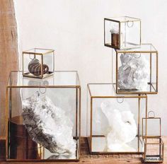 three glass cubes with rocks in them on a wooden table next to a mirror