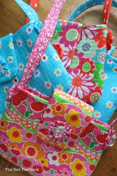 three colorful purses sitting on top of a wooden floor