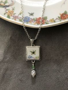 a white plate with a flowered design on it and a chain attached to it