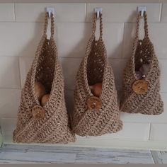 three crocheted purses hanging from hooks on a wall