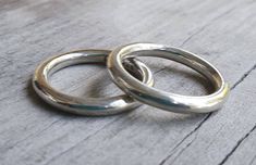 two silver rings sitting on top of a wooden table