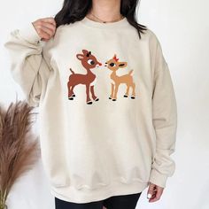 Retro Rudolph And Clarice Sweatshirt, Rudolph Red Nosed Christmas Family Matching Crew Neck Winter Sweater, Casual Cozy Christmas Top, Cute White Christmas Sweatshirt, Cute White Christmas Sweater, White Christmas Sweatshirt Relaxed Fit, Christmas Long Sleeve Tops With Cozy Fit, Cozy Christmas Tops With Relaxed Fit, Cozy Relaxed Fit Christmas Tops, Christmas White Sweatshirt For Loungewear