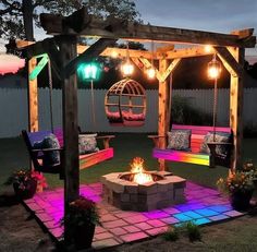 a fire pit in the middle of a yard with lights on it and some chairs around it