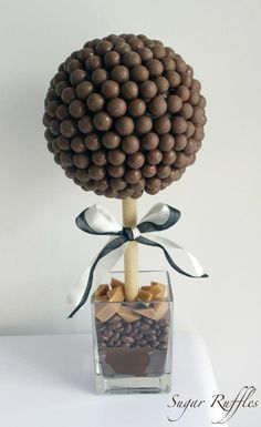 a vase filled with lots of chocolate covered candies on top of a white table