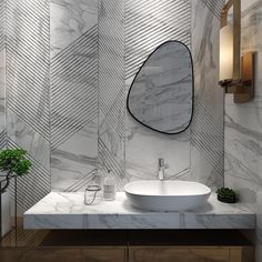 a bathroom with marble counter tops and a round mirror on the wall, along with a potted plant