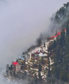 an aerial view of a resort nestled on a snowy mountain side in the foggy weather