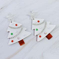 Add a touch of snowy charm to your holiday look with these earrings. The beautiful winter white color base is accented by unique color detailing, making them the perfect accessory for any winter occasion. Spread the magic of the season with these elegant earrings. Dimensions: approximately 1.8" x 2.5" Acrylic Lead and Nickel free Crafted in China White Holiday Dangle Jewelry, White Christmas Festive Earrings, Winter Themed Earrings, White Snowflake Earrings For Christmas, Snowflake Charm Earrings, Christmas Tree Earrings, Winter Wonderland Christmas, Earring Tree, Holiday Looks