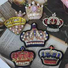 four crown shaped brooches sitting on top of an open book