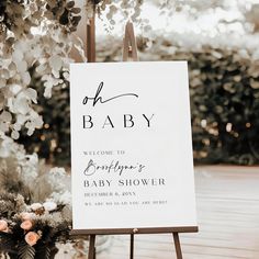 a welcome sign for a baby shower with flowers and greenery in the foreground