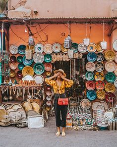 a woman standing in front of a store filled with plates and bowls