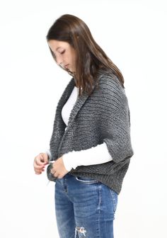 a woman is standing with her hands in her pockets and looking down at her cell phone