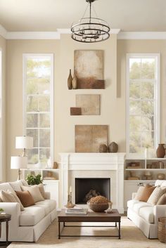 a living room filled with furniture and a fire place under a chandelier in front of two windows