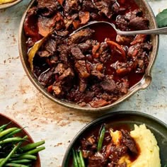 a pot full of beef and mashed potatoes on a table with green beans in it