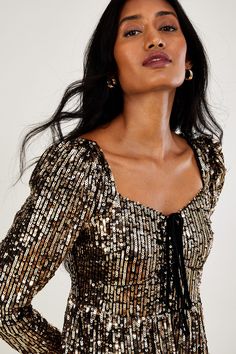 Introducing Georgina: here to mesmerise colleagues at the Christmas work party or dinner guests whilst hosting the NYE party. Drenched in gold sequins, she puts the luxury into luxurious, falling to maxi length with a flatteringly cinched waist. Finished with a sweetheart neckline, puffed shoulders and a tie decoration to the front, she fastens on the reverse with a concealed zipper. Just one of our steps towards a future for sustainable fashion, we introduce S.E.W: our commitment to using more eco-conscious materials in our ranges. This capsule collection is created using fabrics that are both kinder to the planet and have a reduced environmental impact. You’ll see blends of organic and better-sourced cotton, viscose from more responsibly grown forests and recycled polyesters made from po Christmas Work Party, Gold Maxi Dress, Gold Evening Dresses, Evening Dress Collection, Dinner Guests, Nye Party, Occasion Dresses Wedding, Sequin Maxi Dress, Sequin Maxi