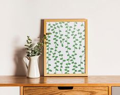 a vase with flowers sitting on top of a wooden table next to a framed photograph