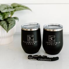 two black wine glasses sitting on top of a table next to a potted plant