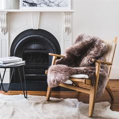 a living room with a fireplace, chair and rug in front of the fire place