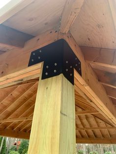 a wooden structure with metal rivets on the top and bottom part, in front of trees