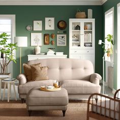 a living room scene with focus on the couch and ottoman, coffee table and potted plant