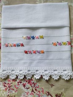 an embroidered piece of cloth with colorful flowers on it sitting on top of a bed