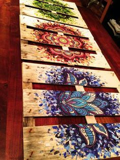 four wooden boards with paintings on them sitting on a table