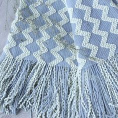 a blue and white blanket sitting on top of a wooden floor next to a plant