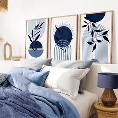 a bed with blue and white sheets in a bedroom next to two pictures on the wall