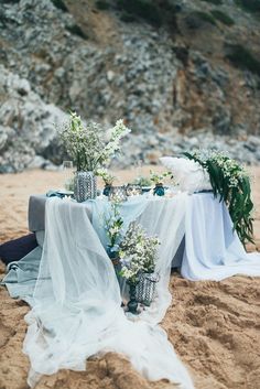 a table with flowers and vases sitting on top of it next to the ocean