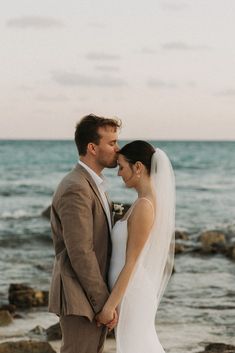 a bride and groom standing on the beach