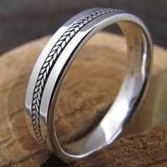 a silver ring with an intricate design on the inside and outside, sitting on top of a piece of wood