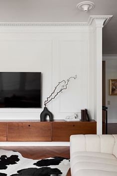 a flat screen tv mounted on the wall above a wooden entertainment center in a living room