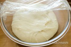 a round dough in a bowl with plastic wrap around it