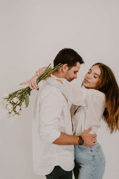 a man and woman embracing each other with flowers in their hair, while the girl is wearing a white shirt