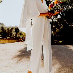 a woman in white jumpsuit holding flowers