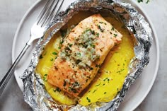 salmon and potatoes in foil on a plate with a fork