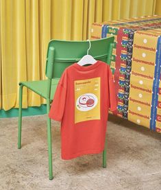 a t - shirt is hanging on a chair in front of a table and yellow curtains