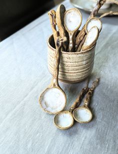 several spoons are sitting on a table with some dried branches in the middle and one is empty