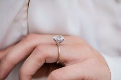 a close up of a person wearing a ring with a heart shaped diamond on it