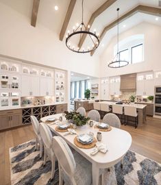 a dining room table with chairs and plates on it in front of an open kitchen