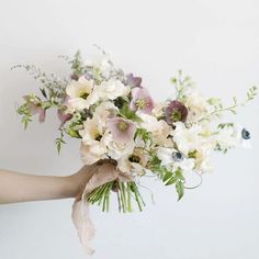 a woman holding a bouquet of white and pink flowers