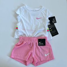 Nike Two Piece Summer Top And Shorts Set - Pink And White. Size 12 Months. 100% Polyester. Dri Fit Material. White Top With Pink Swoosh On The Front And Rainbow Band With Nike Logo Across The Back; Pink Elastic Waist Shorts With White Swoosh. This Is Absolutely Adorable!!! Cute White Short Sets, Spring Playwear Short Set, Spring Short Set For Playwear, Pink Short Set For Playwear, Pink Short Top For Playwear, Short Pink Tops For Playwear, White Short Set For Spring, Nike Cotton Playtime Sets, White Cotton Short Set For Spring