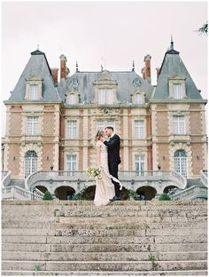 a bride and groom standing on some steps in front of a castle